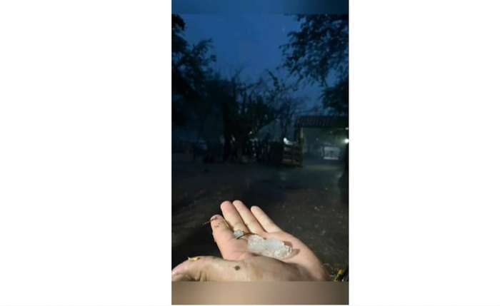 Morador recolhe e mostra na mão pedras de granizo em Major Izidoro