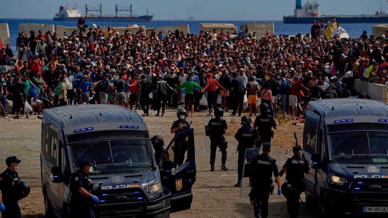 Imigrantes expulsos de praia retornam à área sob escolta policial
