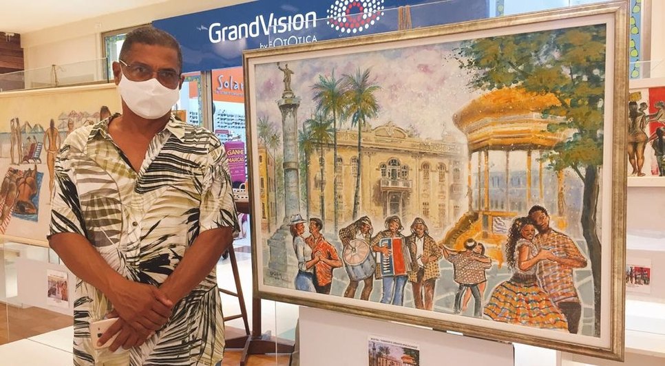 Cartunista Edidelson Silva ao lado de uma de suas obras no Festival Colora / Foto: Foto: Fundação Cultural Cidade de Aracaju (Funcaju)