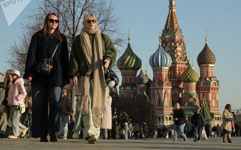Pessoas caminham pela Praça Vermelha em tarde ensolarada de primavera