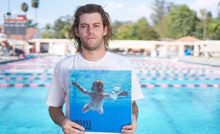 Spencer Elden, o bebê do 'Nevermind', posa com a capa do disco.