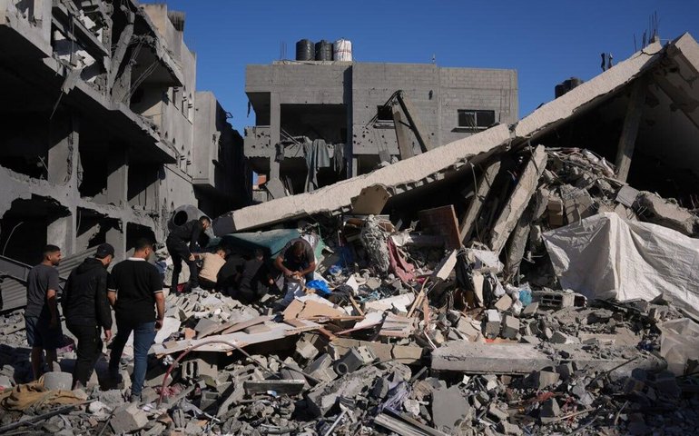 Palestinos inspecionam os escombros de um edifício destruído em um ataque israelense