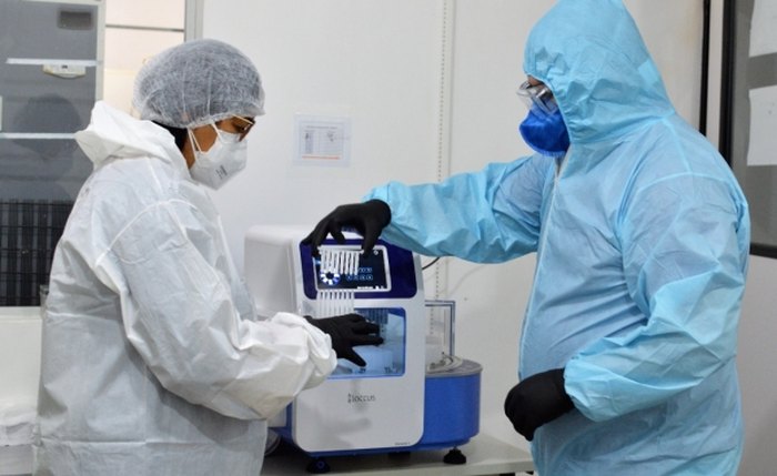 Técnicos com equipamento utilizado em exame para detecção do coronavírus