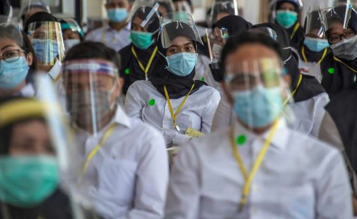 Candidatos a empregos públicos, de máscaras e escudos de proteção contra a propagação do coronavírus, em Surabaya, Indonésia,