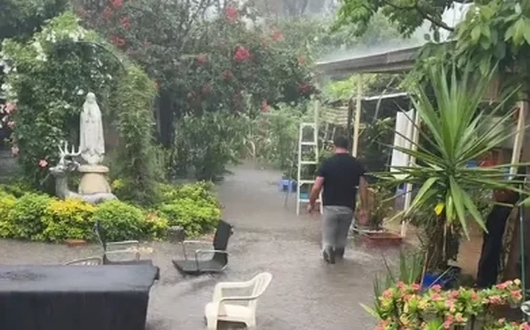 Homem caminha em meio à enchente com água até a altura da panturrilha em Sydney