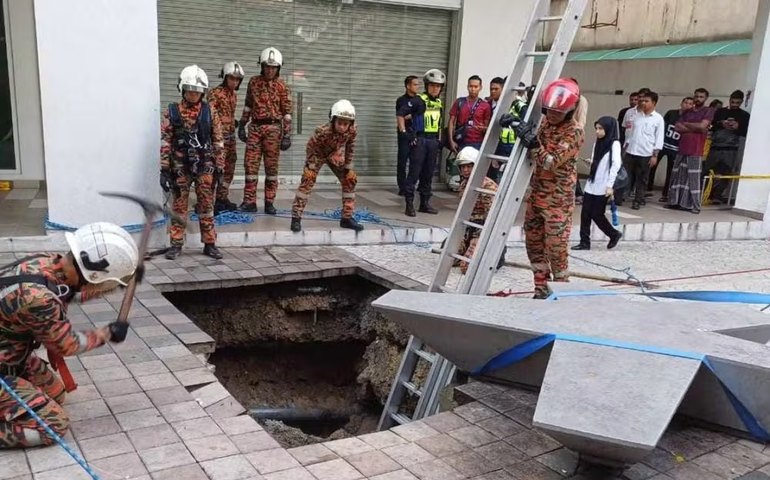 Equipes de resgate correm para salvar mulher engolida por buraco de 8 metros após calçada desabar na Malásia