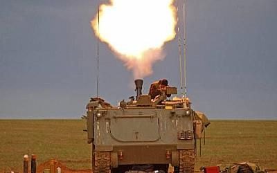 Soldado israelense cobre a cabeça após atirar em tanque de guerra na região da Faixa de Gaza