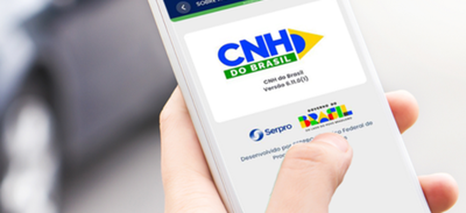Detalhe de uma mão segurando um celular cuja tela exibe o app CNH do Brasil em funcionamento
