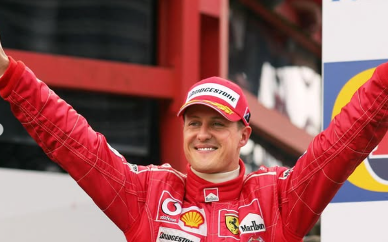 Com ajuda da esposa, Schumacher assina capacete em rara aparição em tributo da F-1