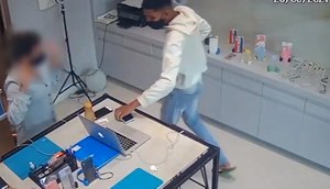 Primeiro dos três suspeitos entra na loja com arma em punho e rende funcionária. / Foto: Imagem: Reprodução/TV Atalaia