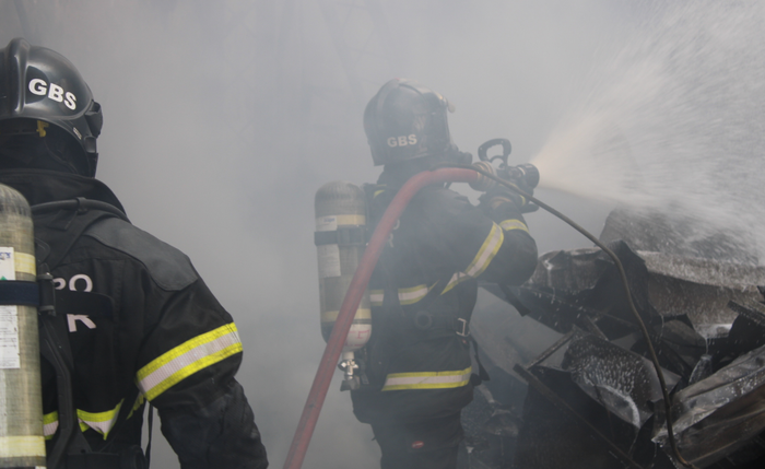 Bombeiros atuando para debelar chamas em incêndio