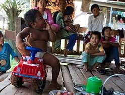 Aldi SugandaRizal, de 2 anos, é visto fumando cigarro enquanto brinca com parentes em maio, em Sekayu, distrito de Sumatra, na Indonésia