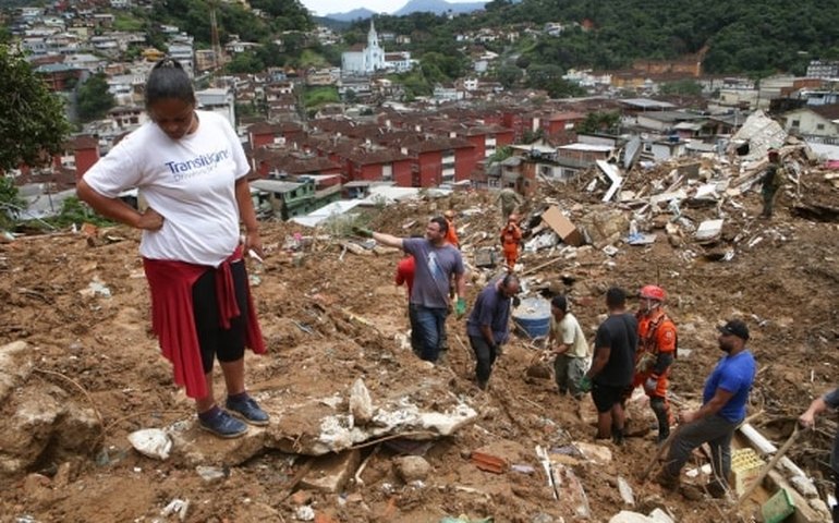 Irmãos cavam a terra em busca do pai que está desaparecido em Petrópolis