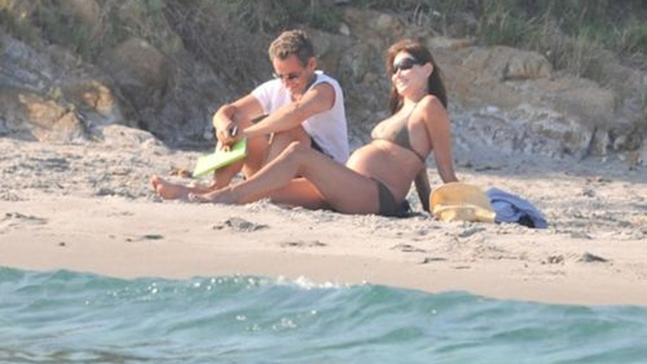 Carla Bruni exibe barrigão e toma banho de sol com Sarkozy na França