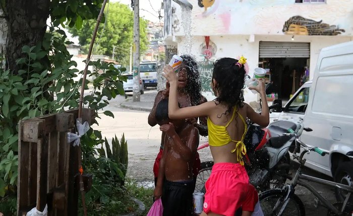 Crianças brincando com água para afugentar o calor