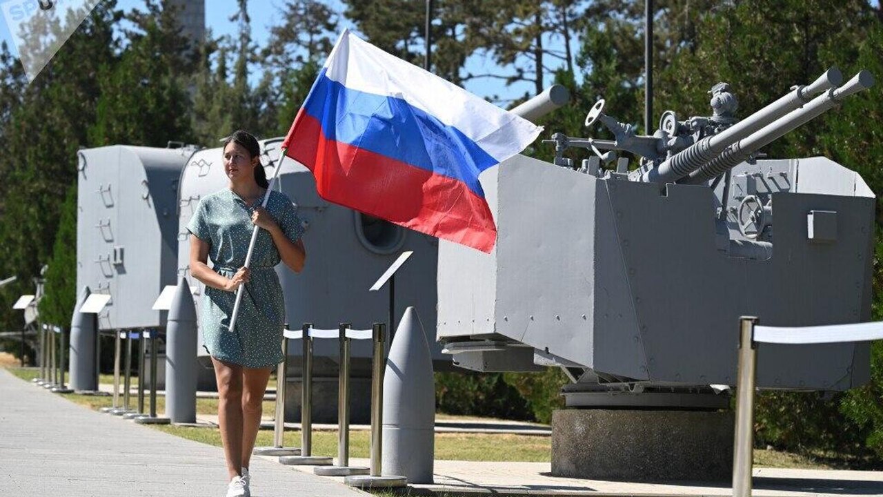 ‍ Uma mulher carrega uma bandeira da Rússia durante as celebrações do Dia Nacional da Bandeira da Rússia no complexo memorial Sapun-Gora