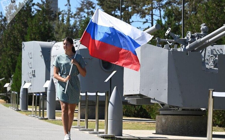 ‍ Uma mulher carrega uma bandeira da Rússia durante as celebrações do Dia Nacional da Bandeira da Rússia no complexo memorial Sapun-Gora